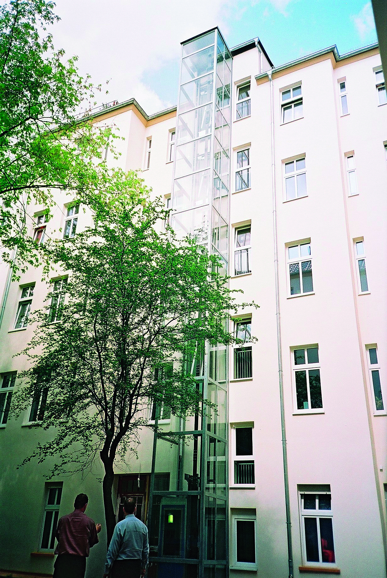 Elevatortårn på gårdsiden af ældre byggeri.